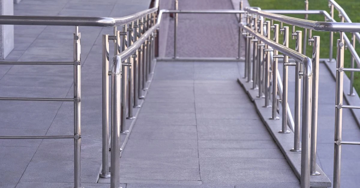 Concrete wheelchair-accessible ramp with metal handrails outside a building