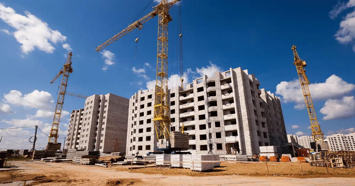 Apartment complex under construction with multiple tower cranes on site.