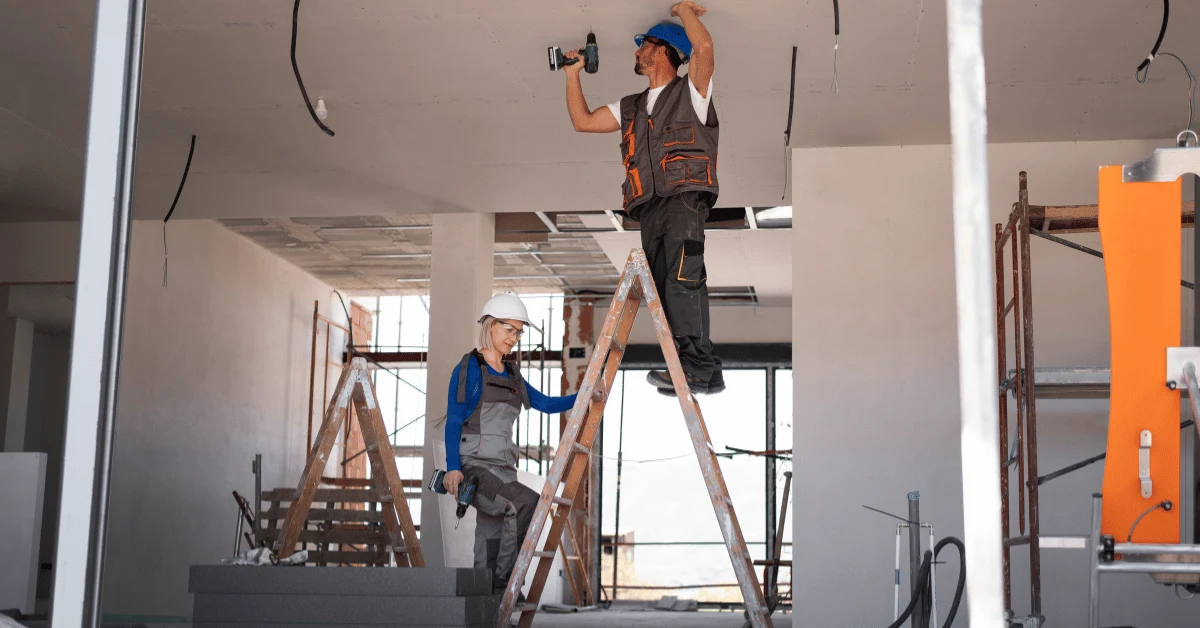 Construction workers installing ceiling fixtures during a nursing home renovation project.