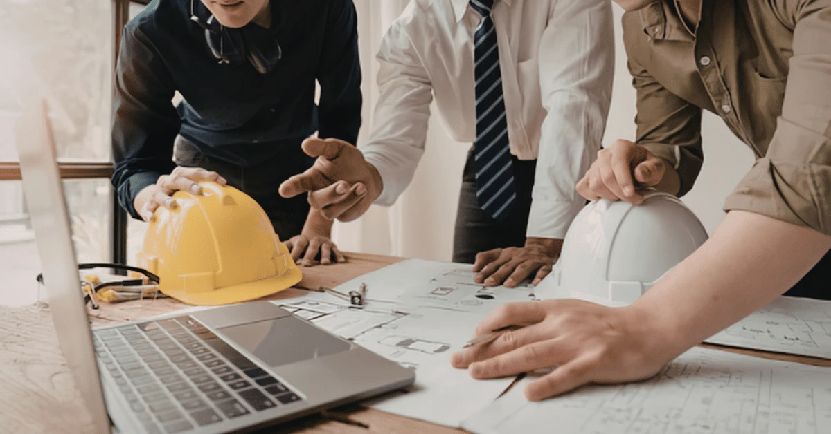Construction professionals reviewing blueprints and project plans at a worksite table.