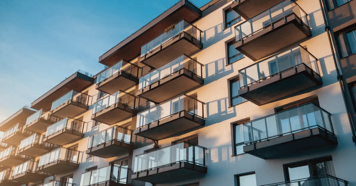 Modern apartment building exterior with balconies in warm evening light.