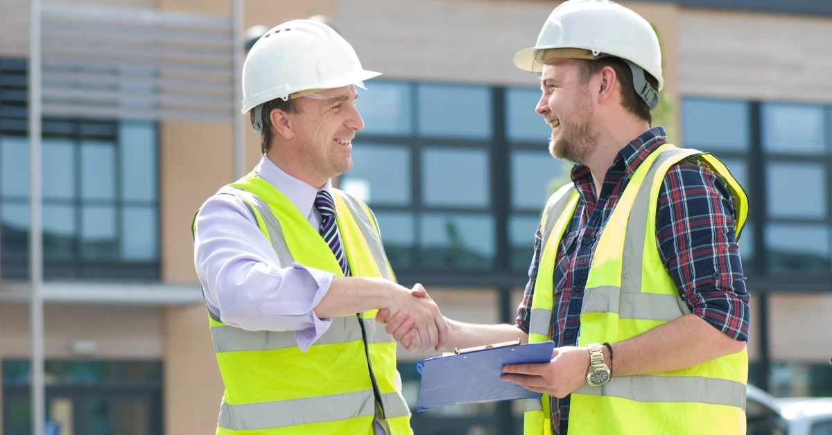 Construction professionals shaking hands outside a commercial building during a general contractor selection meeting in Dallas.